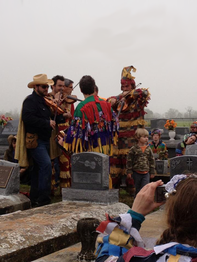 Steve Riley, Joel Savoy, and Wilson Savoy play at the grave of Dennis McGee during Cajun Mardi Gras